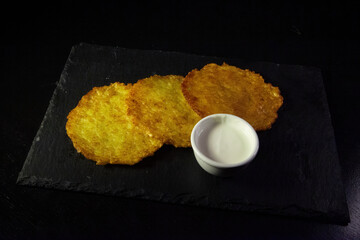 Potato pancakes and sauce on a dark background