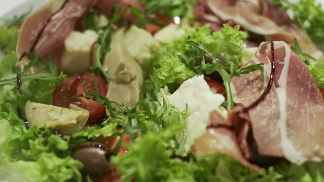Appetizing Salad On Plate. It Consists Of Cheese Olives Meat Salad Leaves Meat. Sauce Is Poured On Salad.