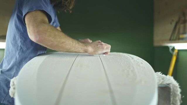 Surfboard shaping, Shaper shaving the stringer of a surfboard. Concept of craftsmanship, small business in America, craftsman at work, millennial worker in USA.  