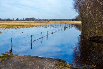 Fence with barbed wire in flooded Swedish field in the spring