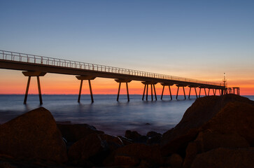 Fototapeta na wymiar Petroleum bridge next to rocks over the mediterranean sea at dawn one winter morning