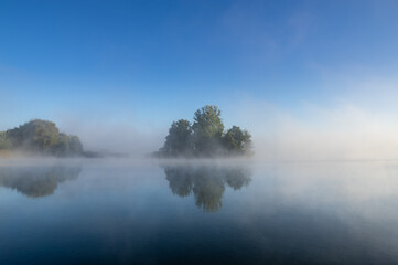 Fototapeta na wymiar island in the lake on a foggy autumn morning