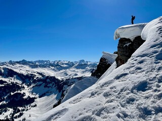 Fototapeta na wymiar Freerider standing on snowcapped cliff close to edge enjoying spectacular views of the Austrian Alps. Vorarlberg, Austria.