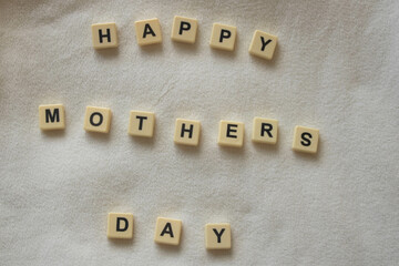 Happy mother's day, written with scrabble / bananagram block letters on soft white fleece background