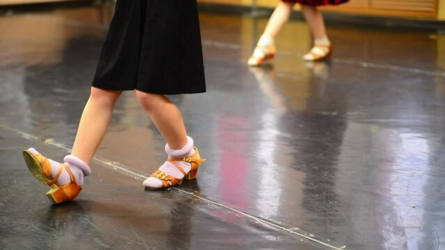 Close-up feet of Caucasian girl in beige high-heels making ballet step in slow motion. Unrecognizable children rehearsing learning dancing in dance studio indoors. Skill and art concept