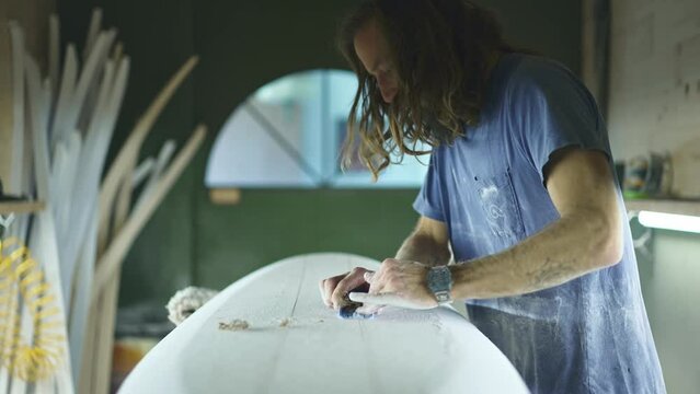 Surfboard shaping, Shaper shaving the stringer of a surfboard. Concept of craftsmanship, small business in America, craftsman at work, millennial worker in USA.  