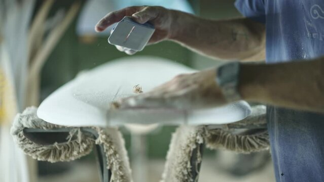 Surfboard shaping, Shaper shaving the stringer of a surfboard. Concept of craftsmanship, small business in America, craftsman at work, millennial worker in USA.  