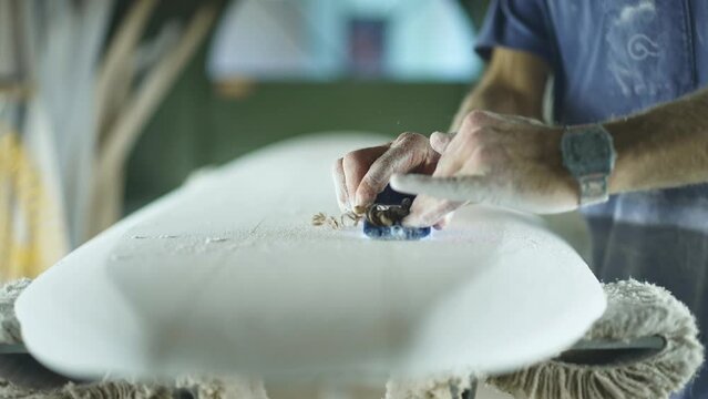Surfboard shaping, Shaper shaving the stringer of a surfboard. Concept of craftsmanship, small business in America, craftsman at work, millennial worker in USA.  