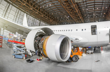 Passenger aircraft on maintenance of engine and fuselage repair in airport hangar. View airplane...