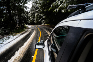 carro viajando en camino de asfalto bajo tormenta de nieve con pinos nevados en bariloche