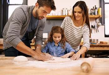 Adding the finishing touches. Shot of a happy family of three baking together in the kitchen.