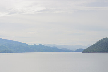 Fototapeta premium Beautiful view of the reservoir in Thailand. Mist cover on mountain at reservoir.
