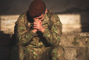 Soldier dressed in camouflage uniform praying to God