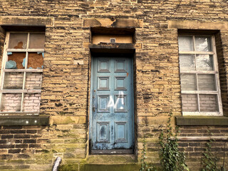 Victorian stone building, with an old blue door, and bricked up windows, in the post industrial town of, Brighouse, UK