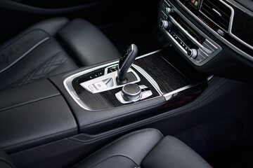 Automatic gear shift knob in a modern sports limousine car. Black car interior.