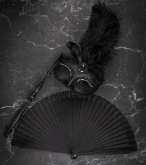 black theatrical mask and fan on a black background