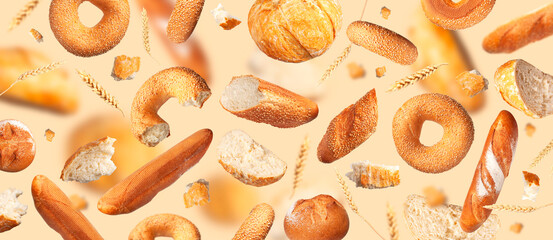 Creative food concept. Various types of bread, ears of wheat flying on beige background. Classic...