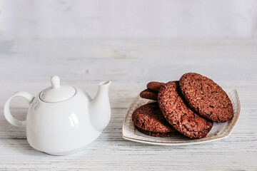 Teapot with tea and chocolate biscuits, spring still life.