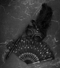 black theatrical mask and fan on a black background