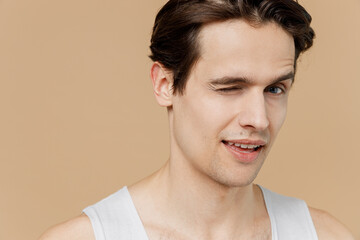 Cropped sexy handsome happy fun young man 20s perfect skin in undershirt wink look camera isolated...