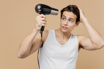 Attractive brunet young man 20s perfect skin in undershirt hold blow dry hair look aside isolated...