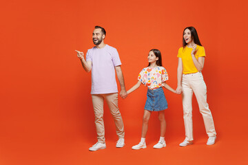 Fototapeta premium Full body young parents mom dad with child kid daughter teen girl wear basic t-shirts walking go hold hands point finger aside on workspace isolated on yellow background. Family day childhood concept