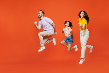 Fototapeta na wymiar Full body side view young happy parents mom dad with child kid daughter teen girl in basic t-shirts run fast hurry up jump high isolated on yellow background. Family day parenthood childhood concept
