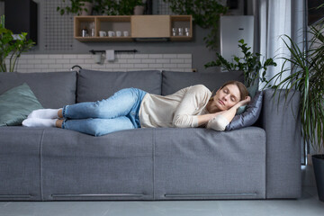 Tired middle aged blonde woman sleeping on sofa after work