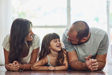 You cant put a price on family time. Shot of a mother and father bonding with their adorable young daughter at home.