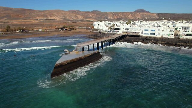 Aerial shot, surfers training surfing on the La Garita beach in Arrieta small coastal spanish village, famous place among locals and tourists, Lanzarote island. Canary, Spain. Travel concept 
