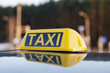 Close Up Of Taxi Cab Sign On a Car Roof. Daytime Traffic On The Background.