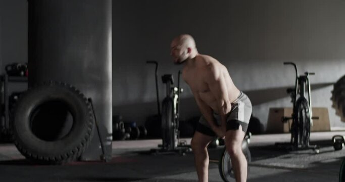 Muscular sportsman doing kettlebell swings in gym