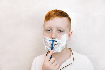 Little boy is shaving his face in the bathroom