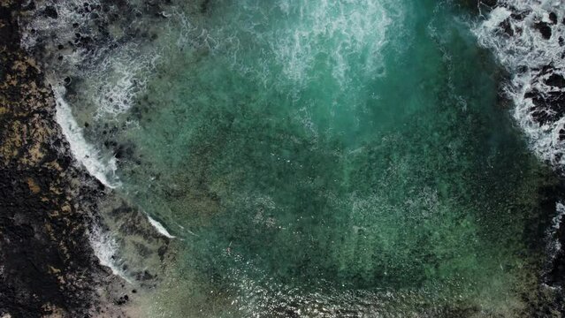 Aerial view Caleta del Mojon Blanco beach, black volcanic stones, bay with turquoise Atlantic Ocean directly above view background. No people. Lanzarote, Canary Islands, Spain
