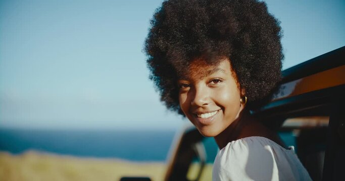 Beautiful young black african american woman smiling and enjoying the wind in her hair on epic summer road trip