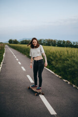 Young stylish girl with skateboard standing outdoors. 