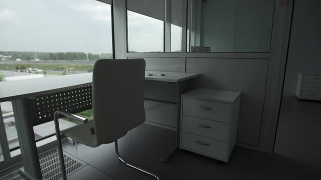 Minimal background image of empty office workplace by window with white desk behind glass wall, copy space. Lost work, unemployment, economic crisis concept.