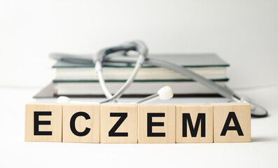 Wooden block form the word eczema with stethoscope on the doctor's desktop. Medical concept. Healthcare conceptual for hospital, clinic and medical business. - obrazy, fototapety, plakaty