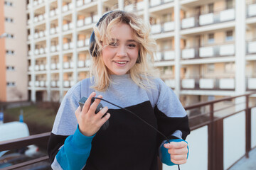 Smiley caucasian blonde-hared young woman listening to her favorite album on cassette player....