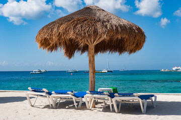 Tiki hut with lounge chairs in front of ocean, Cozumel, Mexico