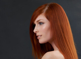 Scarlet stunner. Studio shot of a gorgeous young redheaded woman against a black background.