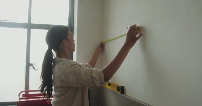 Mid Adult Female Measuring Wall for Home Renovations
