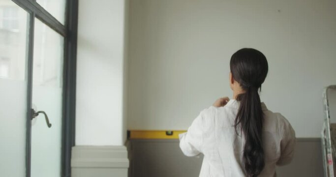 Black Adult Female Measuring Wall for Home Renovations