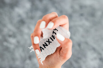 hand holding Anxiety text on scrunched up piece of paper, mental health concept