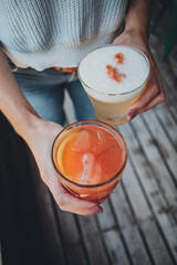 a woman holding two glasses of colorful and fresh drinks