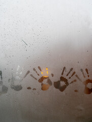 vidrio de ventana empañado por lluvia afuera con manos marcadas en el interior vertical