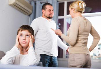 Fototapeta premium Sad desperate little boy during parents quarrel in home interior