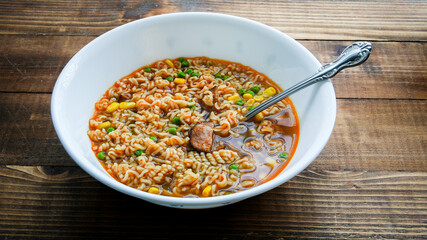 Asian noodle soup with corn, peas and sausages