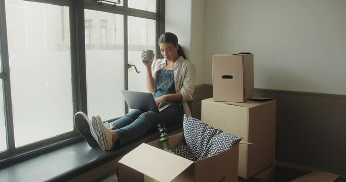 Black Female using Laptop in New Home Planning Surrounded by Boxes