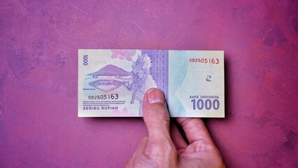 Fototapeta premium Indonesian Rupiah the official currency of Indonesia. Man's hand is making a payment. Business Loan Income Money Investment Economy and Finance Concept Uang 1000 1.000 Rupiah. Prosperity Concept.